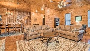 A wooden interior with a sectional sofa, a round coffee table, and a staircase. - Broken Bow Cabin w/ Deck, Hot Tub & Fire Pit! (Broken Bow)