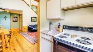 A kitchen with a white stove, wooden cabinets, and a red rug. - 2 Mi to Parkway! Pet-friendly Cabin w/ Hot Tub (Sevierville)