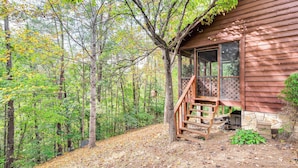 A cabin with a porch, surrounded by a forest. - 2 Mi to Parkway! Pet-friendly Cabin w/ Hot Tub (Sevierville)
