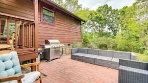 A wooden deck with a grill, wicker furniture, and a chair. - 2 Mi to Parkway! Pet-friendly Cabin w/ Hot Tub (Sevierville)
