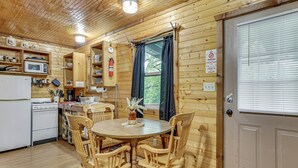 Innenansicht einer Holzhütte mit Küche, Essbereich und einer Tür mit Fenster.
