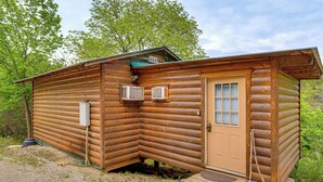 Eine Blockhütte mit Tür, zwei Fenstern und einer kleinen Veranda.