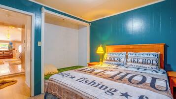 Una habitación con una cama, una mesita de noche, una lámpara y una puerta que da a otra habitación.