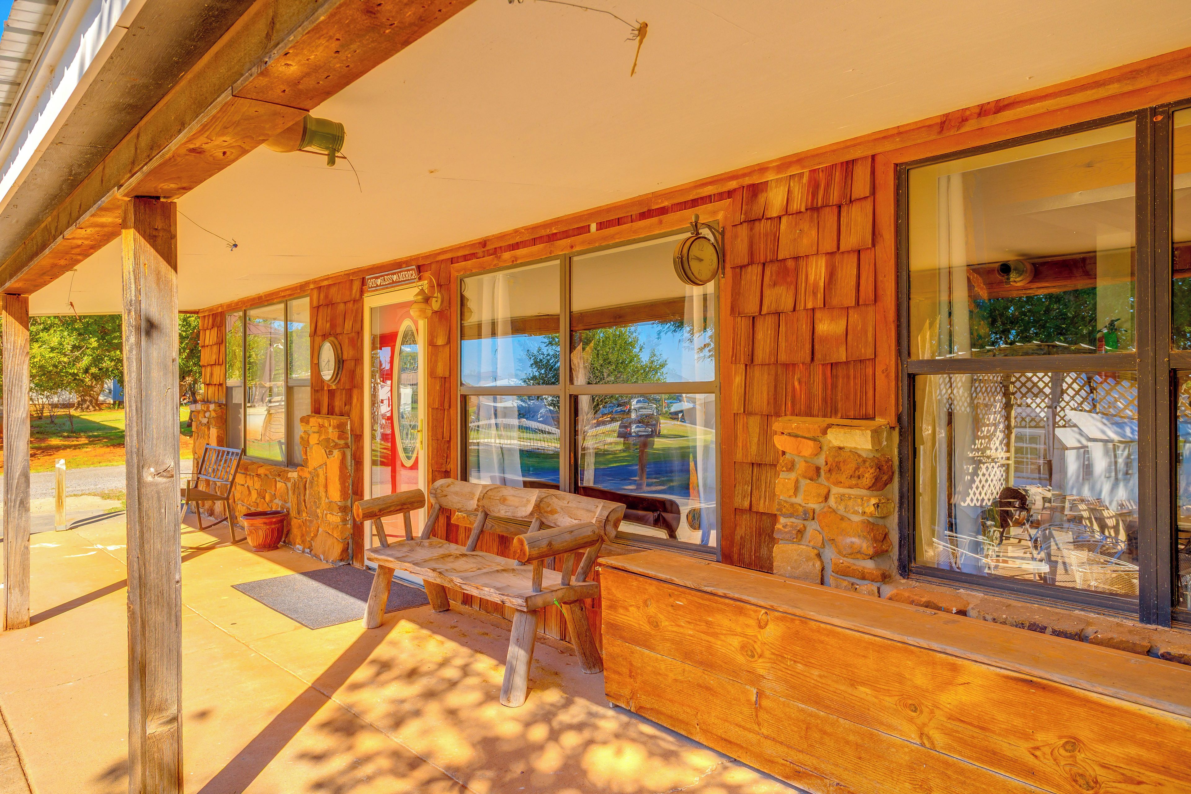 A wooden exterior with large windows, a stone wall, and outdoor seating.