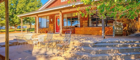 A wooden building with a porch, outdoor seating, and a stone staircase leading to the entrance.