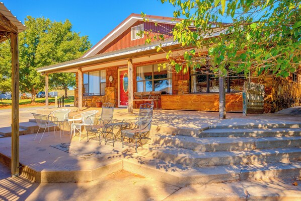 A wooden building with a porch, outdoor seating, and a stone staircase leading to the entrance.
