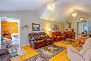 A living room with leather sofas, a wooden floor, a fireplace, and a mounted deer head. - Rustic Home w/ Patio, 1 Mi to Sunset Beach! (Butler)