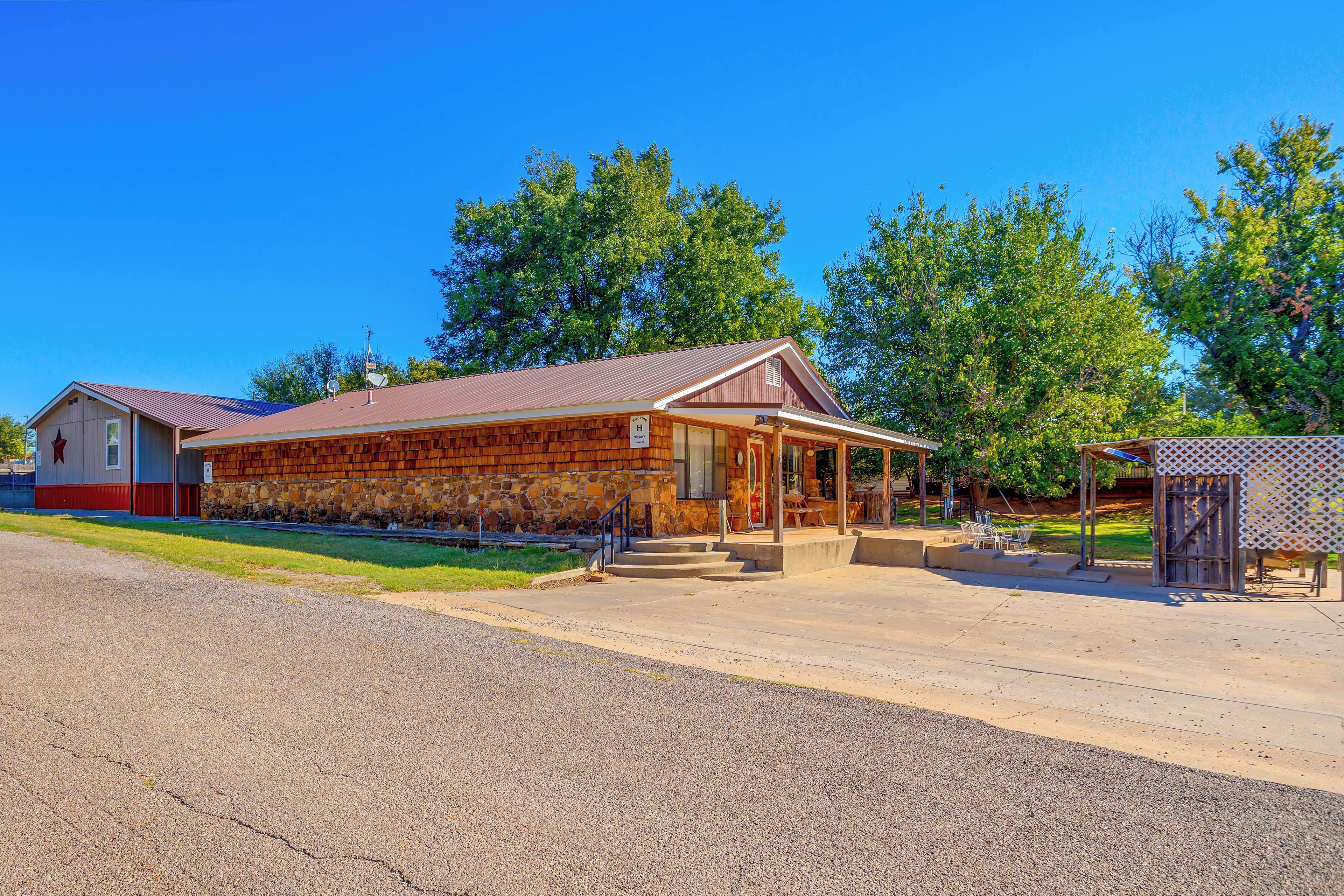 A rustic building with a stone facade, a metal roof, and a porch with outdoor seating.
