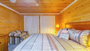 A wooden room with a bed, a sofa, and a wardrobe.
