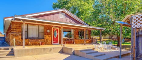A rustic building with a wooden exterior, a red door, and a covered patio area with outdoor seating.