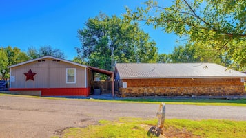 A building with a red star on the side, a covered porch, and a stone wall.