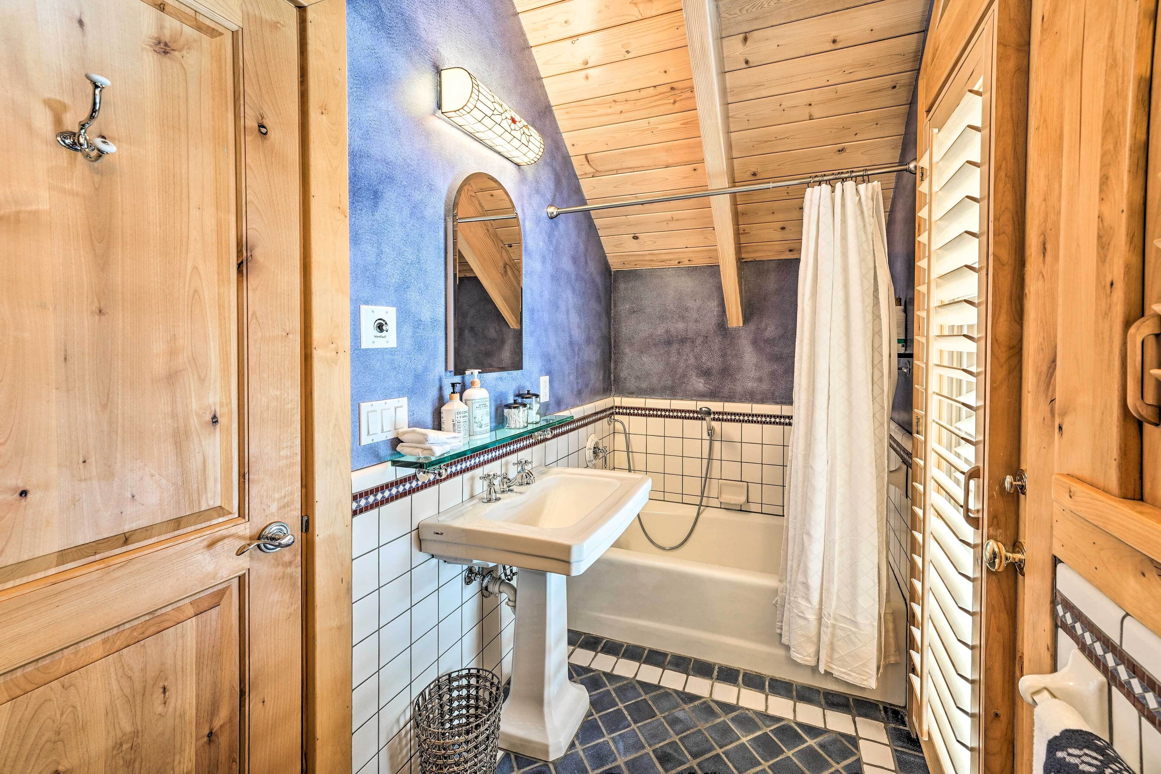 Une salle de bain avec un plafond en bois, un lavabo, une baignoire et un rideau de douche.