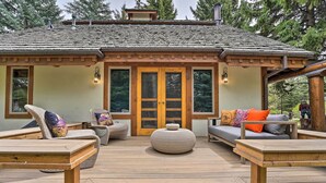 Une terrasse en bois avec un espace salon extérieur, comprenant des chaises et un canapé, ainsi qu’une grande porte-fenêtre.