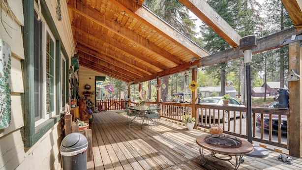 A wooden deck with a covered area, outdoor seating, and a trash can. - Mountain Top's Ponderosa Getaway Near Dome Rock! (Springville)