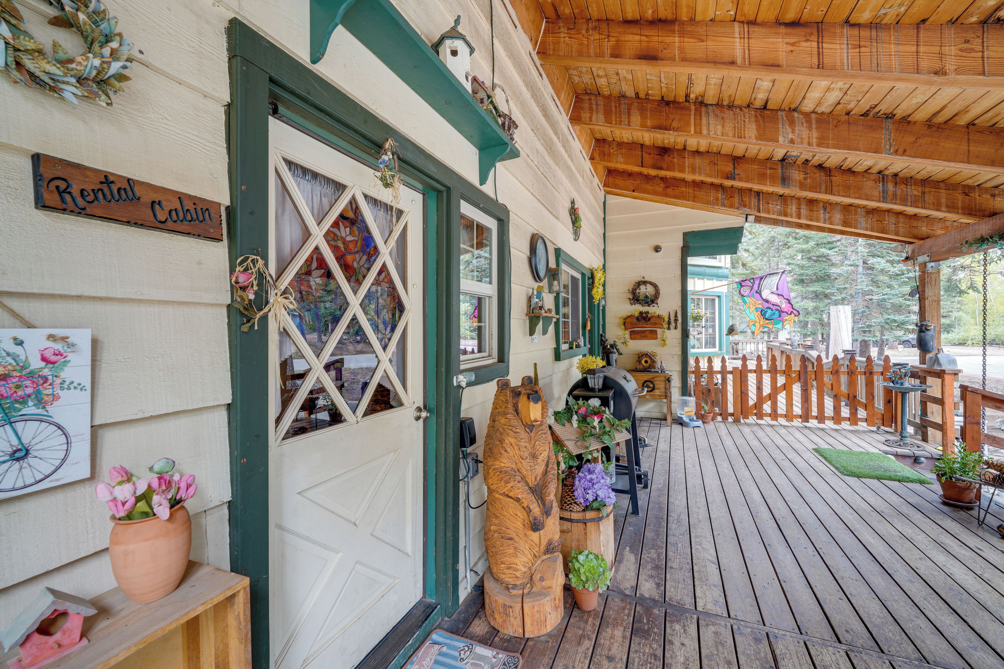 A wooden cabin with a porch, a sign reading "Rental Cabin," and a large window with a diamond pattern.