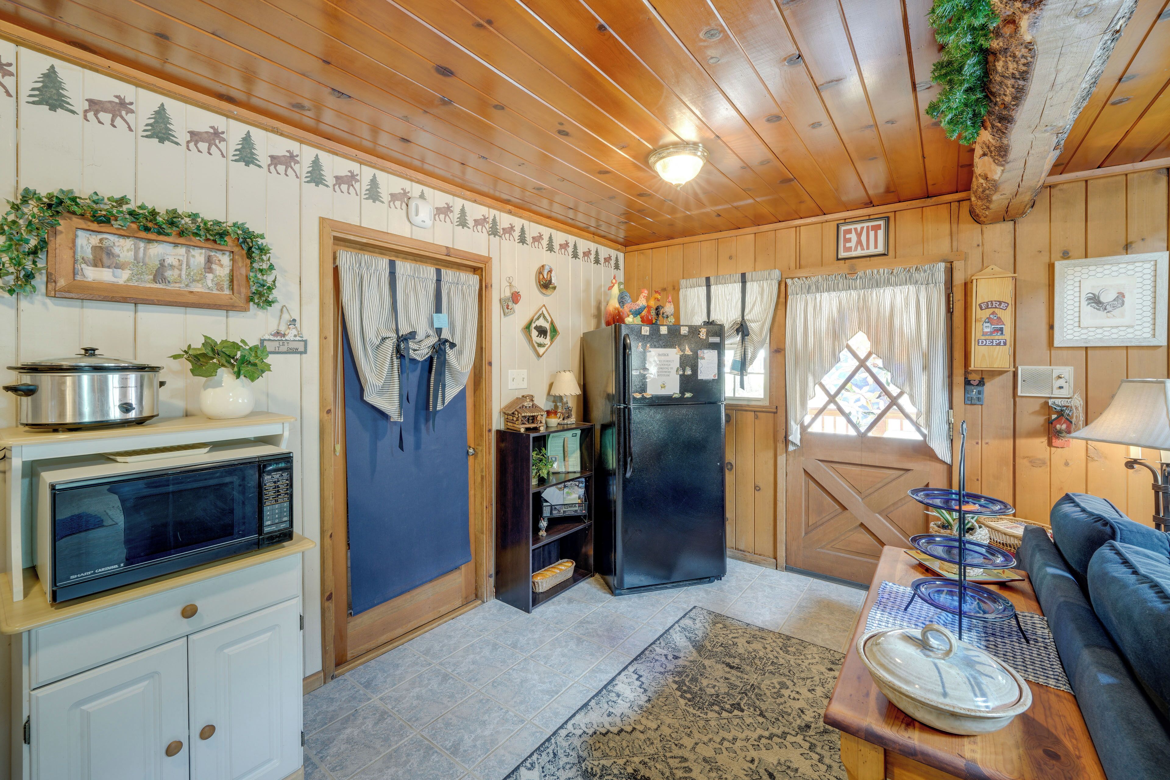 A cozy cabin interior with a kitchen area featuring a microwave, refrigerator, and wooden cabinets.