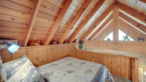 A cozy attic bedroom with wooden walls and a sloped ceiling, featuring a bed with patterned bedding and a small window. - Mountain Top's Ponderosa Getaway Near Dome Rock! (Springville)