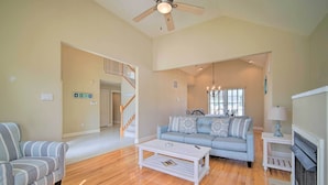 A spacious living room with a light blue sofa, a striped armchair, and a white coffee table. A wooden staircase is visible in the background, leading to another level. - Spacious Brigantine Home ~ 1 Block to Beach! (Brigantine)