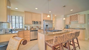 A modern kitchen with wooden cabinets, stainless steel appliances, a central island with bar stools, and pendant lighting. - Spacious Brigantine Home ~ 1 Block to Beach! (Brigantine)