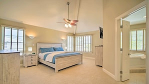 A bedroom with a bed, bedside tables, a ceiling fan, and a bathroom visible through an open door. - Spacious Brigantine Home ~ 1 Block to Beach! (Brigantine)