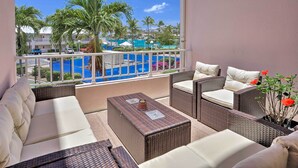 A balcony with wicker furniture, a view of a pool, and palm trees. - Tropical St. Thomas Resort Getaway w/ Pool Access! (St. Thomas)