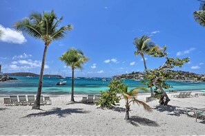 A beach with palm trees, lounge chairs, and boats in the water. - Tropical St. Thomas Resort Getaway w/ Pool Access! (St. Thomas)