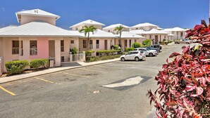 A row of modern, single-story buildings with a uniform architectural style, featuring balconies and a parking lot with several cars. - Tropical St. Thomas Resort Getaway w/ Pool Access! (St. Thomas)