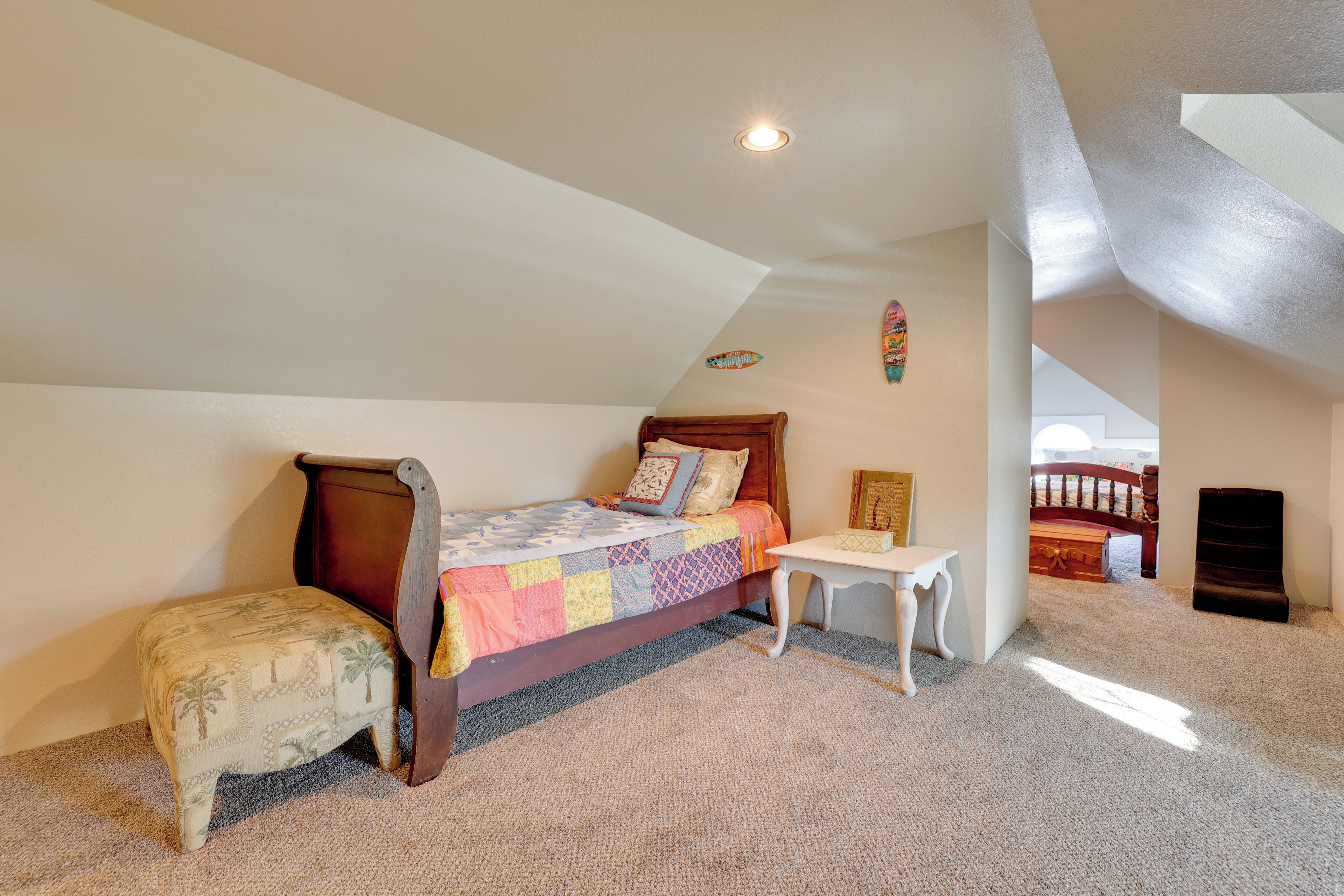 A bedroom with a bed, a small table, a bench, and a ceiling light.