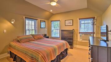 A bedroom with a bed, dresser, and two windows.