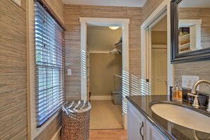 Une salle de bain moderne avec un grand miroir, un lavabo avec un robinet et une poubelle.