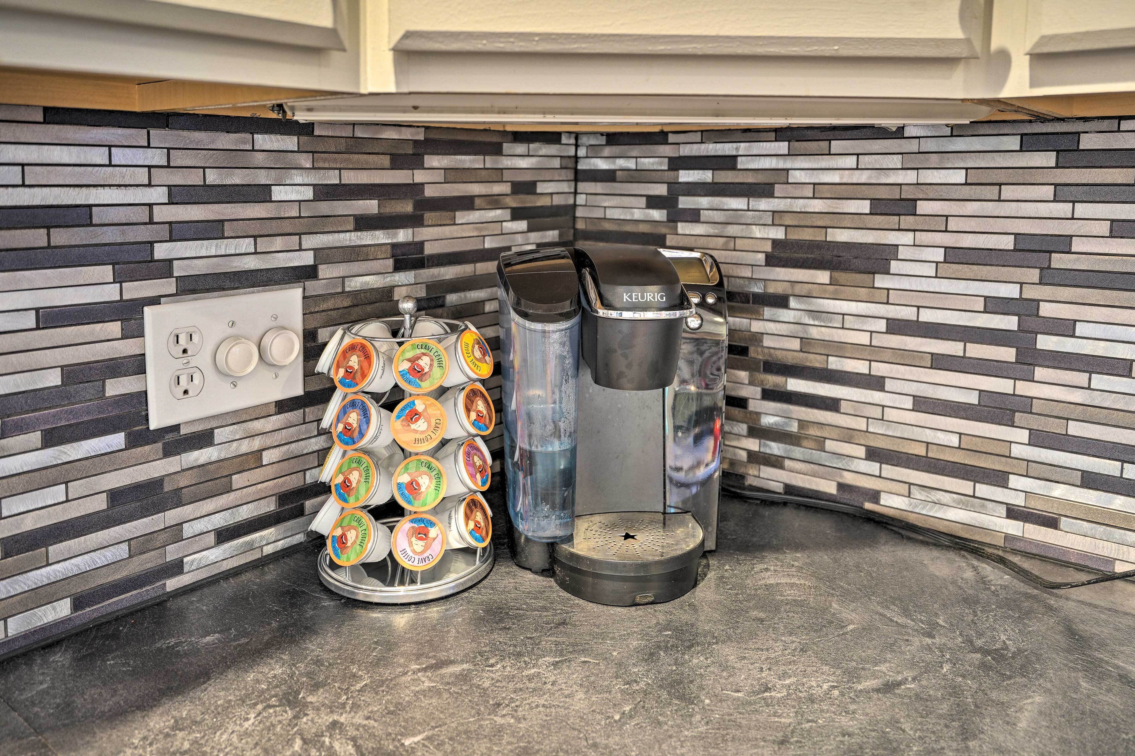 A coffee station with a Keurig coffee maker, a water dispenser, and a mug rack with various coffee pods.
