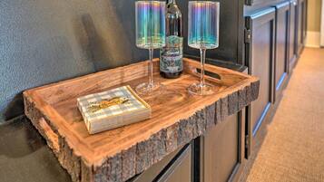 A wooden tray with a bottle of wine and two glasses on a kitchen counter.