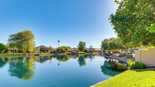 A serene residential area with a calm water feature reflecting the surrounding houses and greenery. - Private Patio & Grill: Lakefront Chandler Home (Chandler)