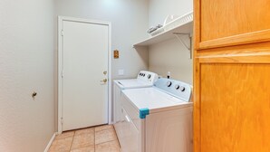 A laundry room with a white door, a washing machine, and a dryer. - Private Patio & Grill: Lakefront Chandler Home (Chandler)