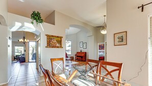 A dining area with a glass table, wooden chairs, and a hanging plant. - Private Patio & Grill: Lakefront Chandler Home (Chandler)