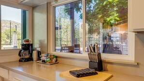 A kitchen with a large window, a coffee maker, a cutting board, and a knife block.