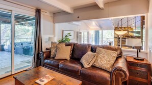 A spacious living room with a leather sofa, a wooden coffee table, and a staircase leading to an upper level.