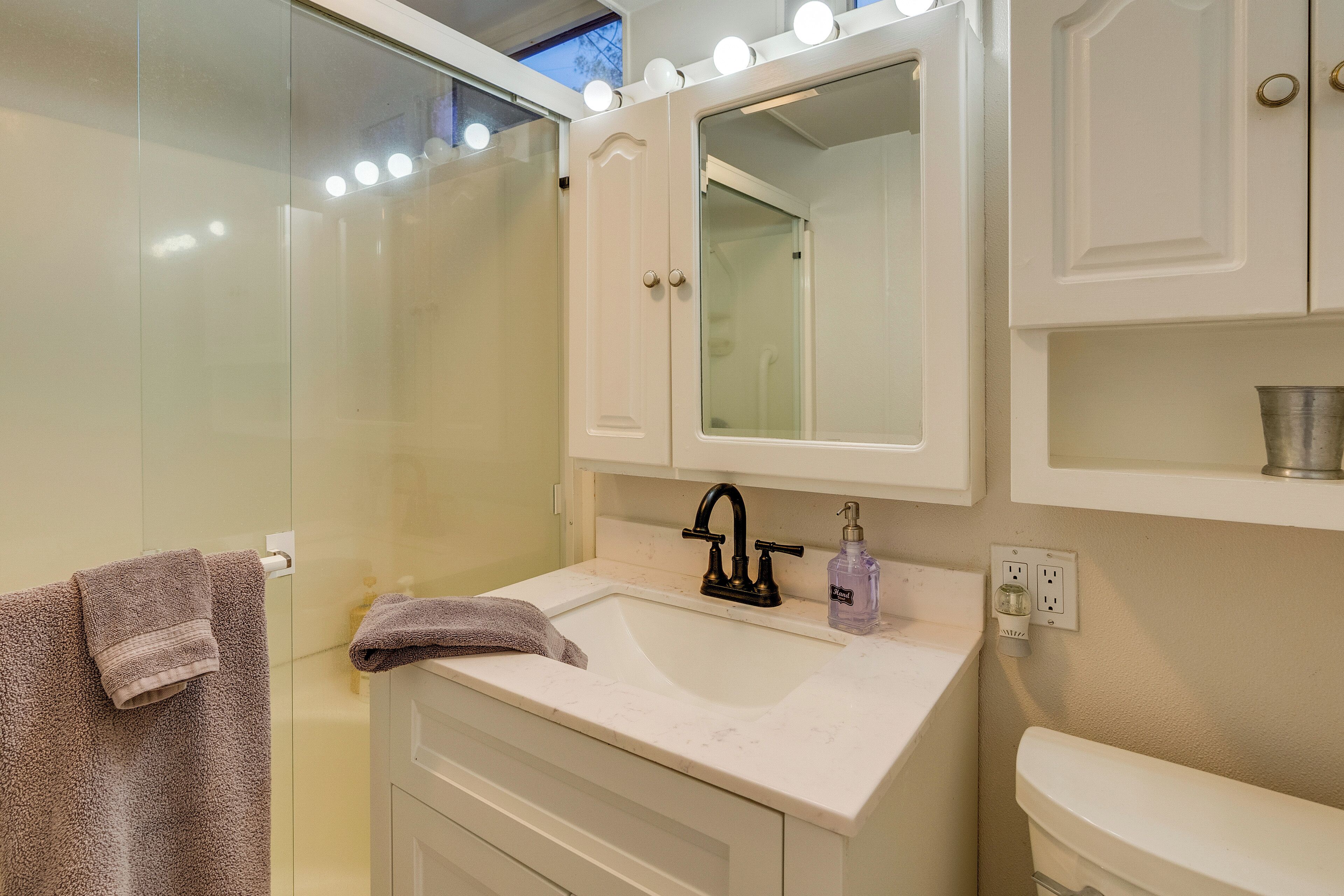 A bathroom with a white sink, a mirror, and a glass shower enclosure.