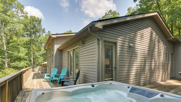 Eine Holzterrasse mit Whirlpool, zwei Stühlen und einer überdachten Veranda.