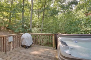 A wooden deck with a hot tub and a covered grill.