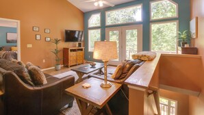 Ein Wohnzimmer mit einer Couch, einem Couchtisch, einem Fernseher und einem Deckenventilator.