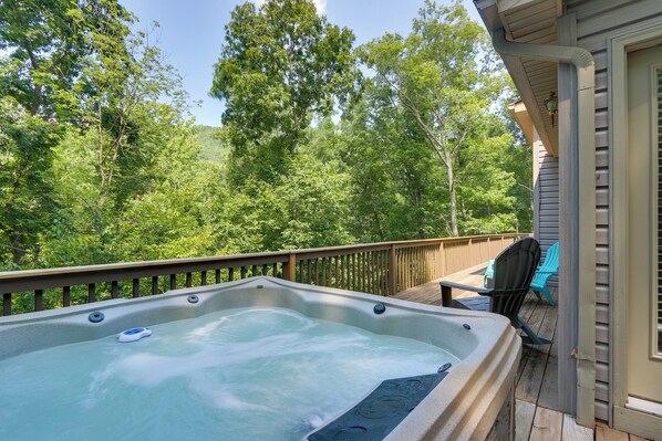 A hot tub on a wooden deck with a view of a forested area.