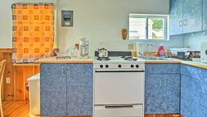 A kitchen with a white stove, blue cabinets, and a window. - Lakefront Rumney Retreat w/ Shared Dock & Beach! (Rumney)