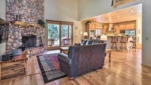 A spacious living area with a stone fireplace, a leather sofa, and a wooden coffee table.