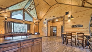 A spacious kitchen with wooden cabinets, a large island, and a dining area with wooden chairs and a table. - Ouachita Mtn Home: Near ATV & Hiking Trails! (Hodgen)