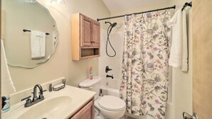 Un baño con lavamanos, inodoro, ducha y espejo.