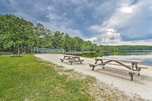 A lakeside picnic area with picnic tables and a volleyball net. - Cozy Poconos Ranch Home w/ Pool Access, Near Lake! (Gouldsboro)