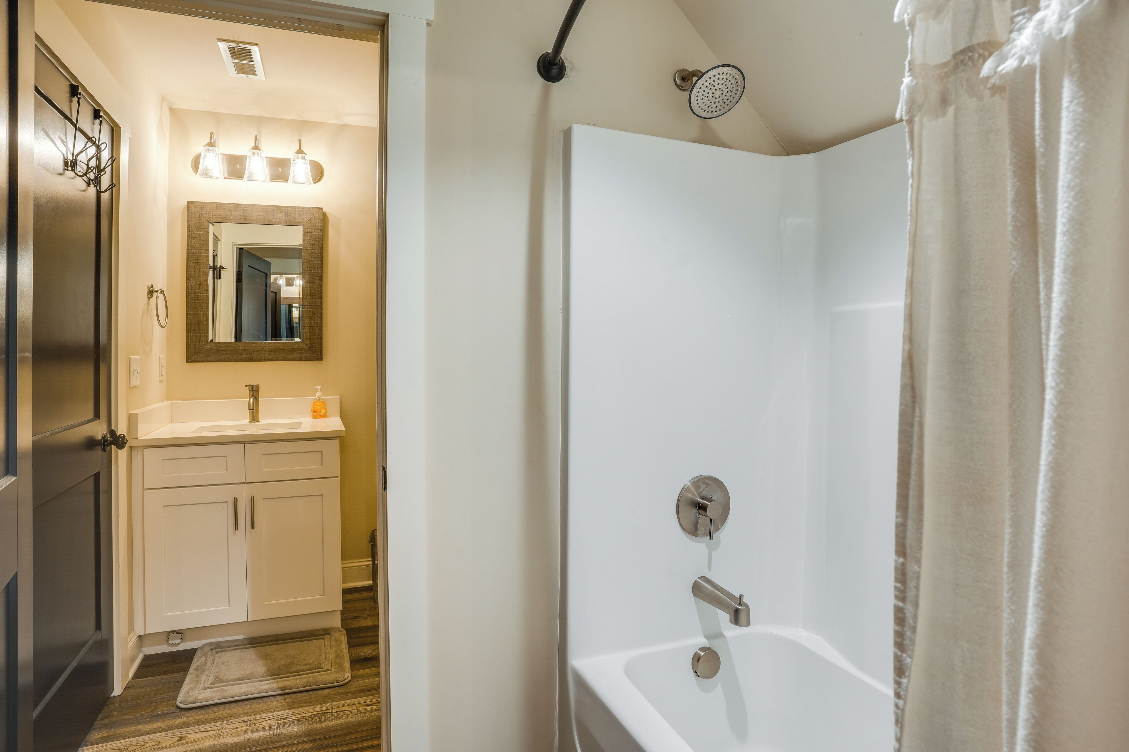 A bathroom with a shower, a sink, a mirror, and a towel rack.