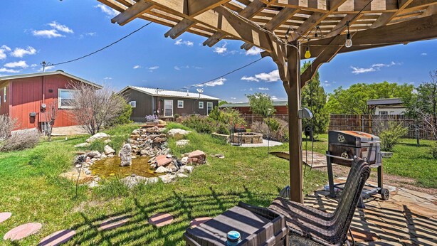 Ein überdachter Patio-Bereich mit Grill und einem kleinen Teich.