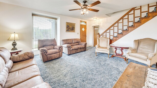 A living room with a ceiling fan, a staircase, and a door leading to another room. - Charming Trinidad Home ~ 2 Mi to Main Street! (Trinidad)